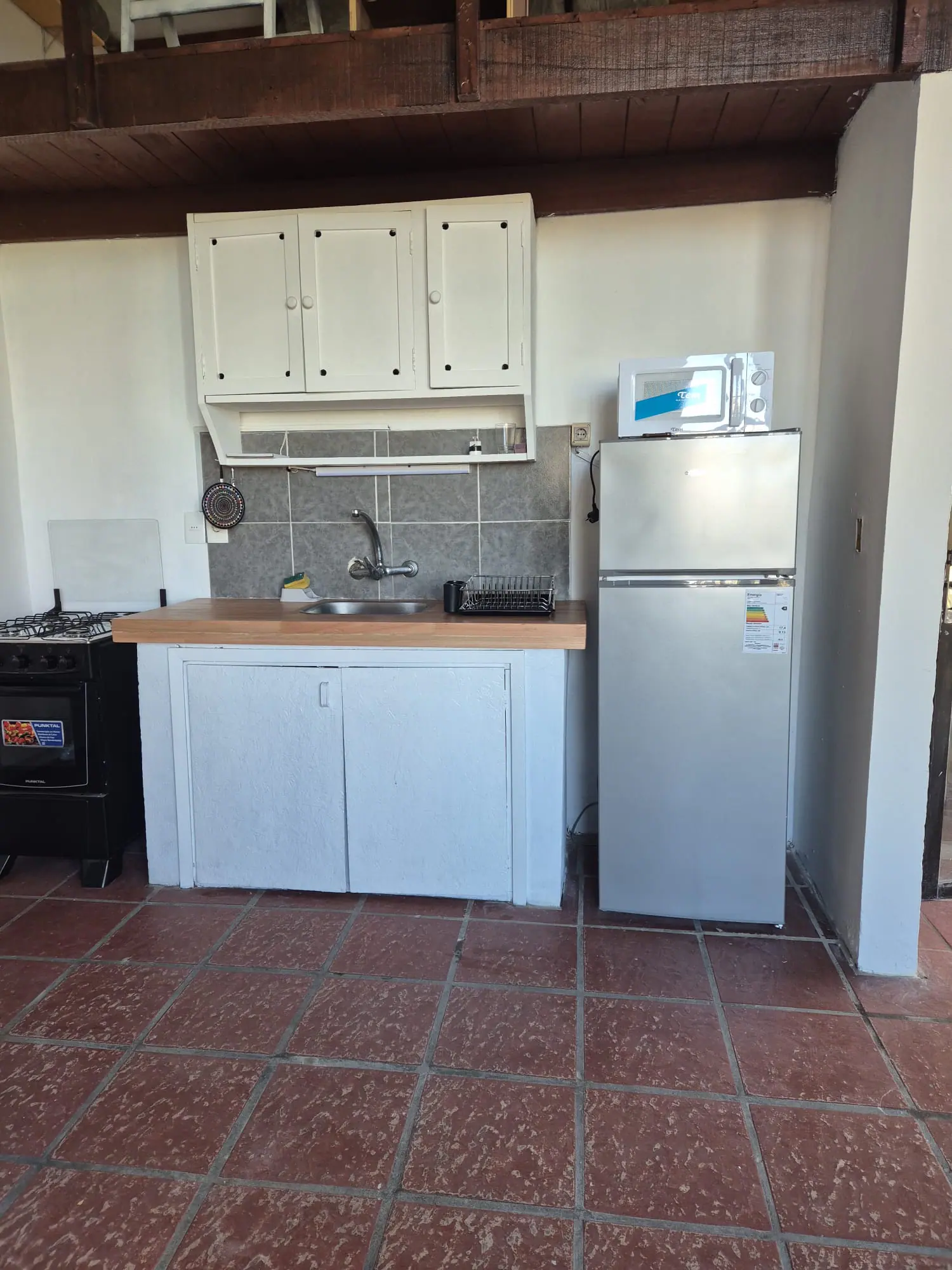 Cocina con mesada de madera, cocina a gas con horno, heladera con freezer y microondas